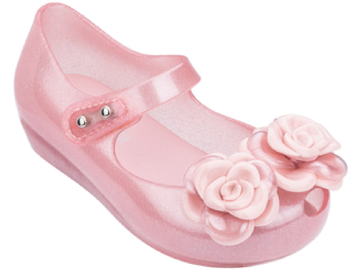 Sandalia rosa brillante de Mini Melissa para niña con adornos de flores y correa.