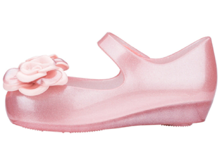Sandalia rosa brillante de Mini Melissa para niña con adornos de flores y correa.