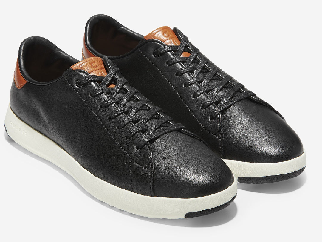 Tenis Cole Haan Grand Pro para hombre en color negro con suela blanca y detalles en color café.