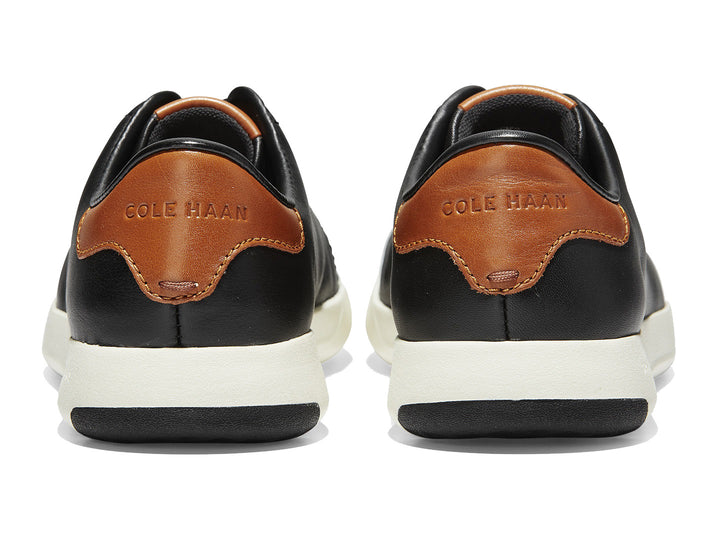 Tenis Cole Haan Grand Pro para hombre en color negro con suela blanca y detalles en color café.