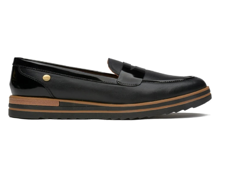 Zapato tipo mocasín de piel color negro con suela marrón.