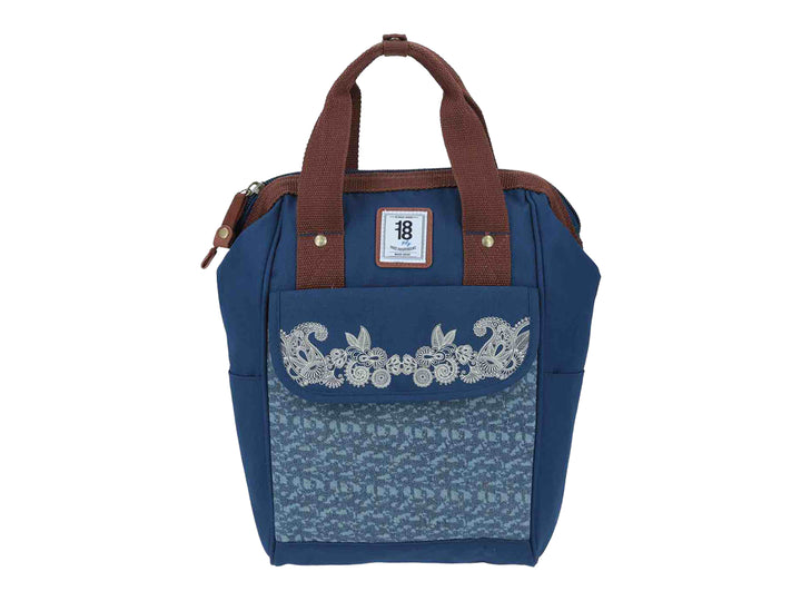 Mochila infantil azul con bordado floral blanco en el frente y asas color marrón.