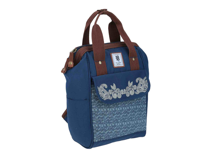 Mochila infantil azul con bordado floral blanco en el frente y asas color marrón.