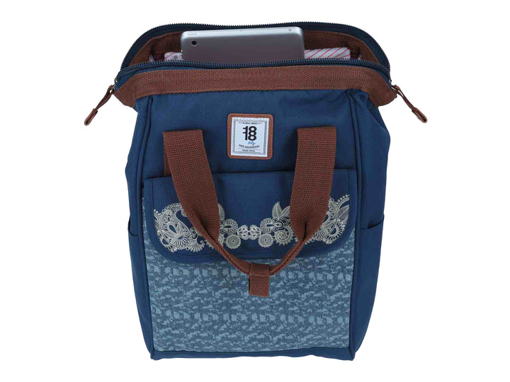 Mochila infantil azul con bordado floral blanco en el frente y asas color marrón.