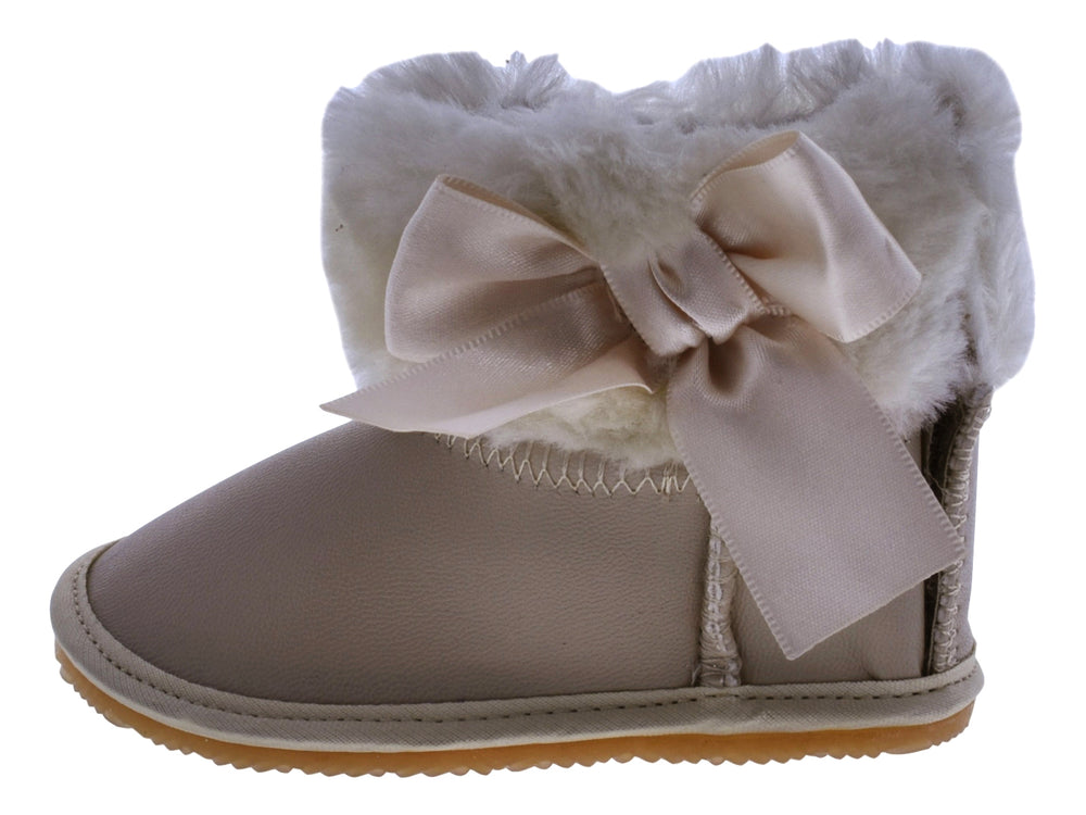 Par de botas color oro para bebé con detalles de moño y borde de peluche blanco.