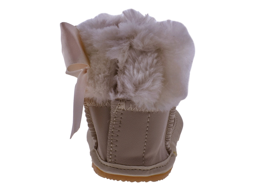 Par de botas color oro para bebé con detalles de moño y borde de peluche blanco.