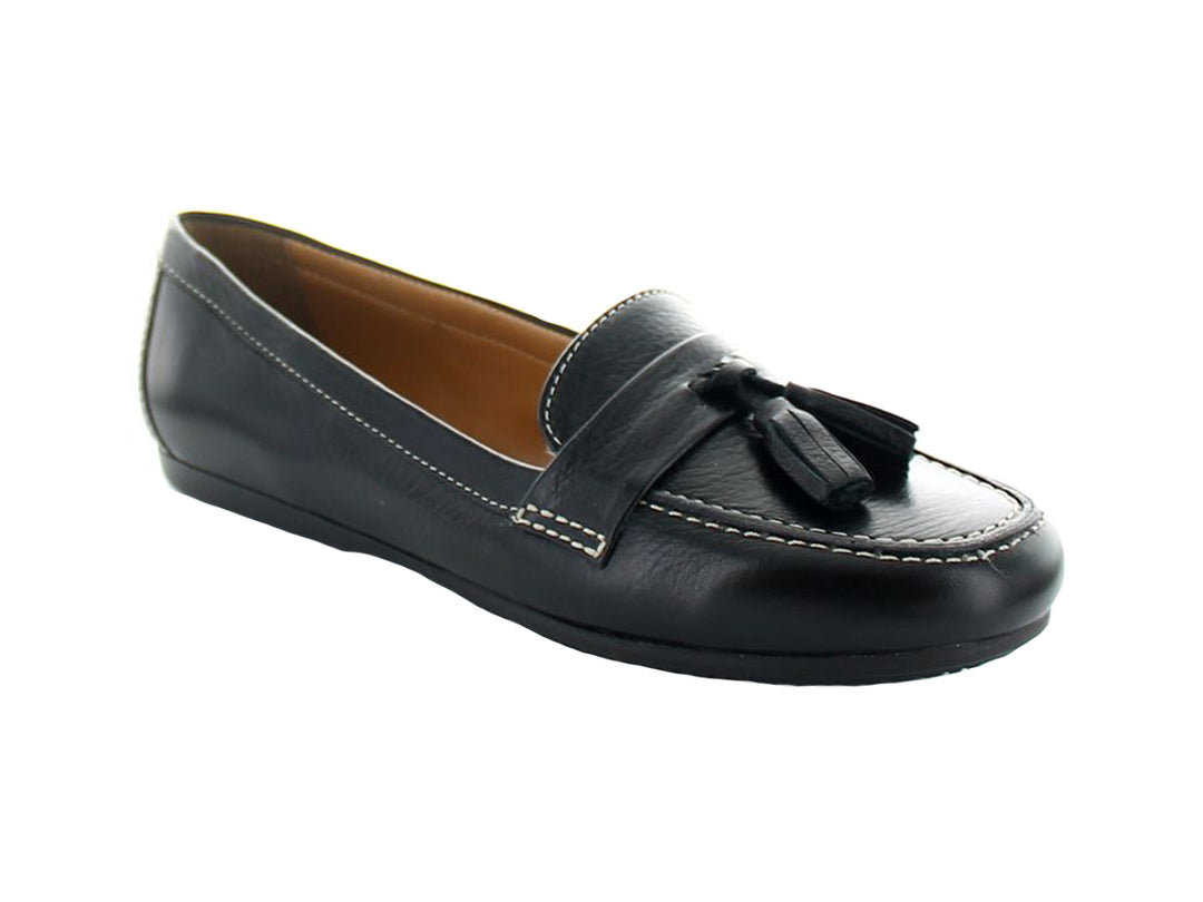 Zapato mocasín de cuero negro con borlas decorativas y costuras blancas contrastantes.