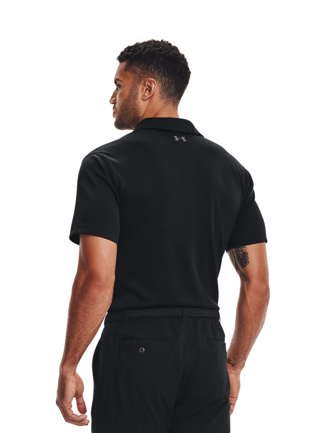 Hombre vistiendo playera polo deportiva Under Armour de color negro con detalles en gris.
