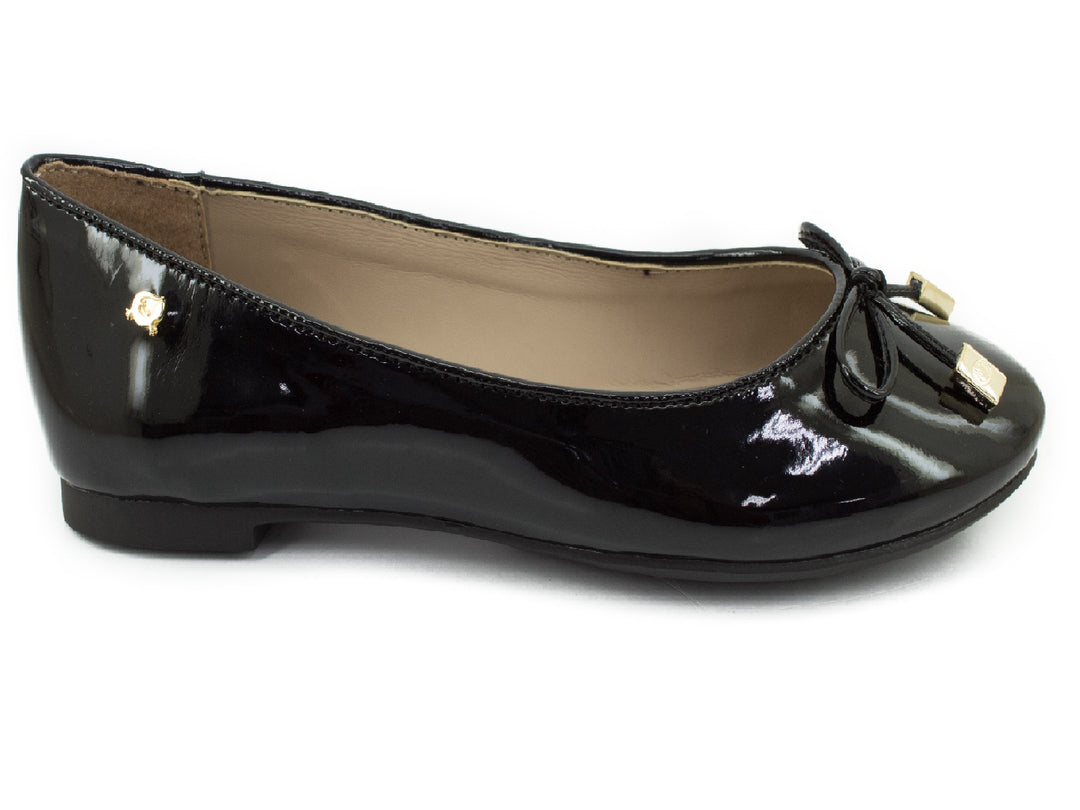 Zapato plano de mujer en charol negro con un moño y detalles decorativos en color dorado.