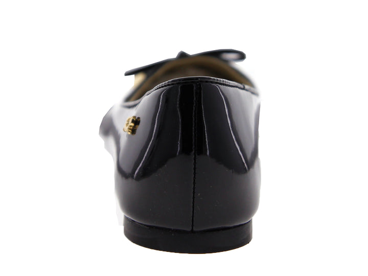 Zapato plano de mujer en charol negro con un moño y detalles decorativos en color dorado.