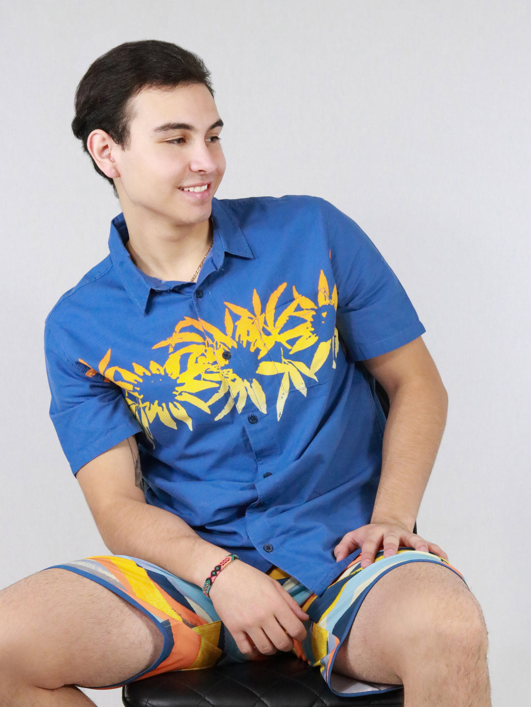 Hombre vistiendo camisa azul de manga corta con estampado floral amarillo en el pecho.
