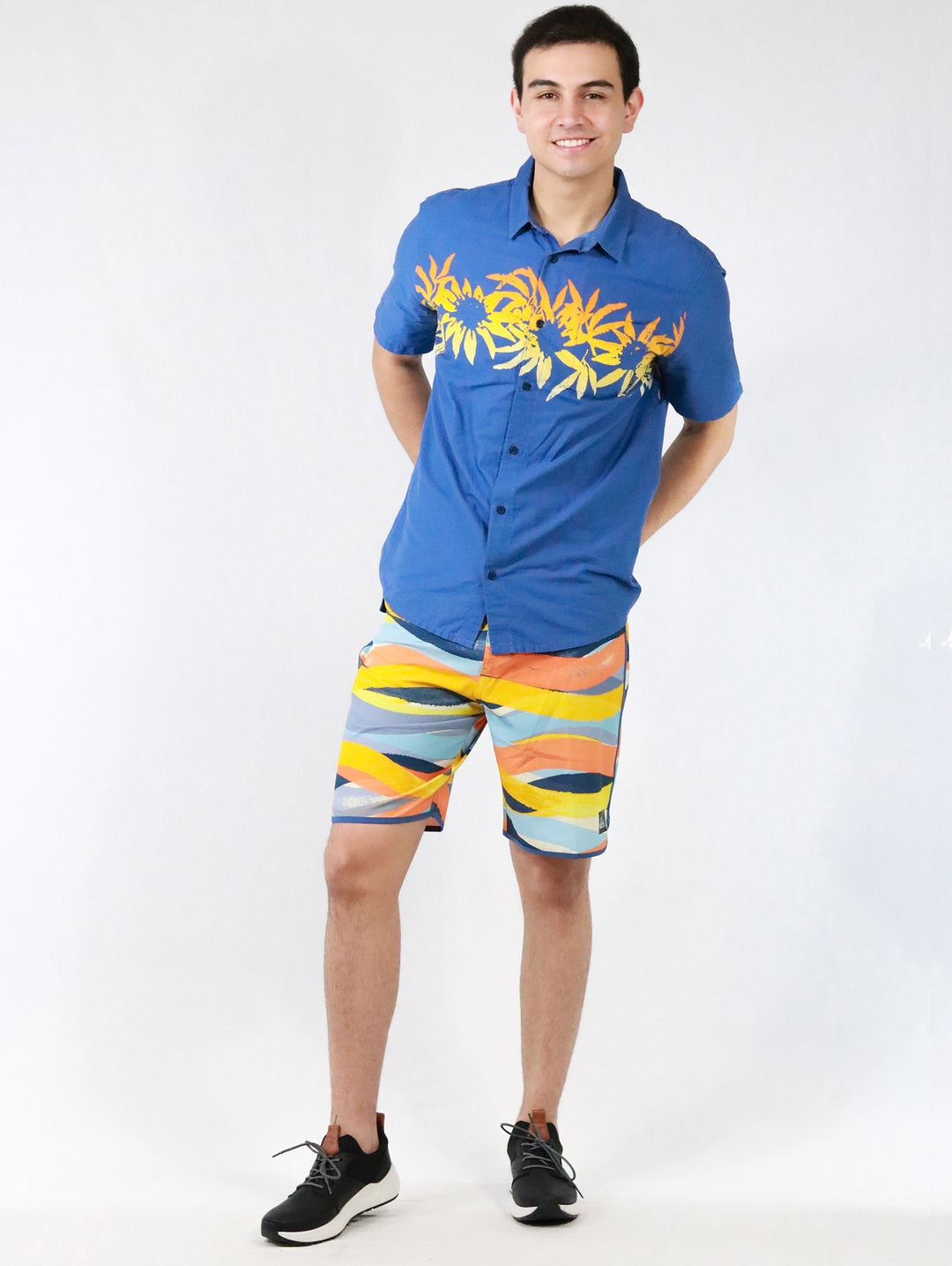 Hombre vistiendo camisa azul de manga corta con estampado floral amarillo en el pecho.