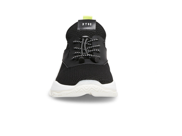 Tenis Steve Madden Isles Flyknit en color negro con suela blanca robusta y detalle amarillo neón en el talón.