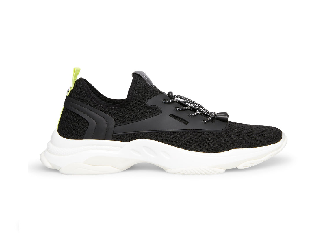 Tenis Steve Madden Isles Flyknit en color negro con suela blanca robusta y detalle amarillo neón en el talón.