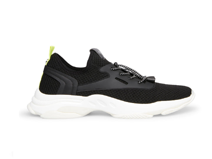 Tenis Steve Madden Isles Flyknit en color negro con suela blanca robusta y detalle amarillo neón en el talón.