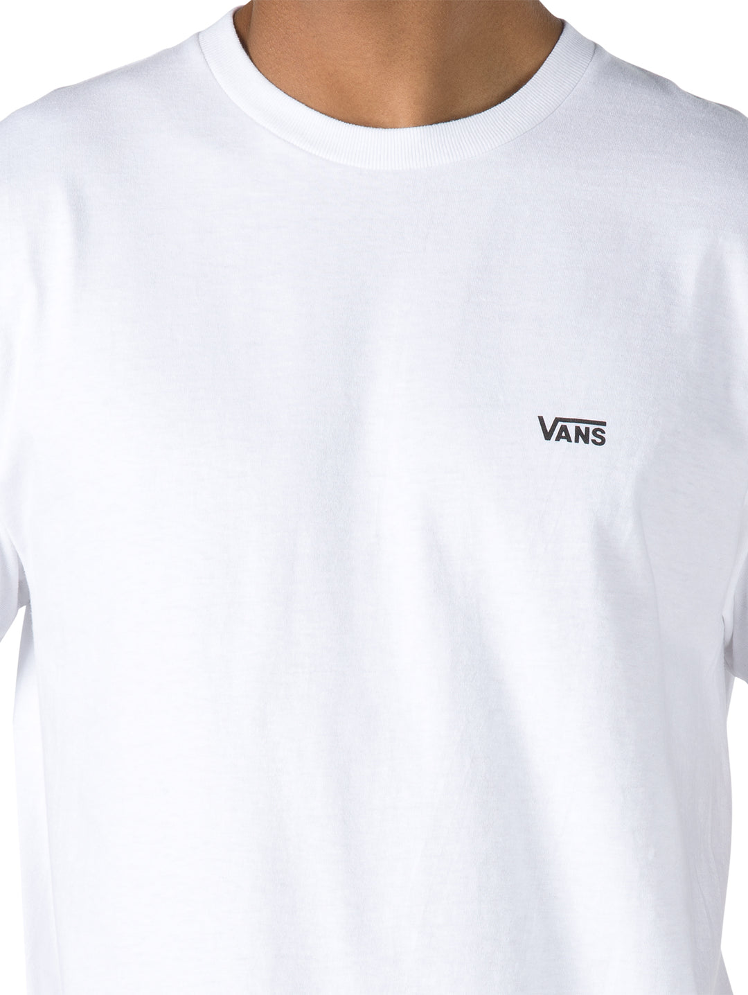 Hombre vistiendo una camiseta blanca de manga corta con logotipo pequeño de Vans en el pecho izquierdo.