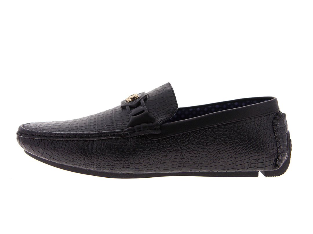 Zapatos mocasines negros con textura de piel de cocodrilo y detalle metálico en la parte superior.