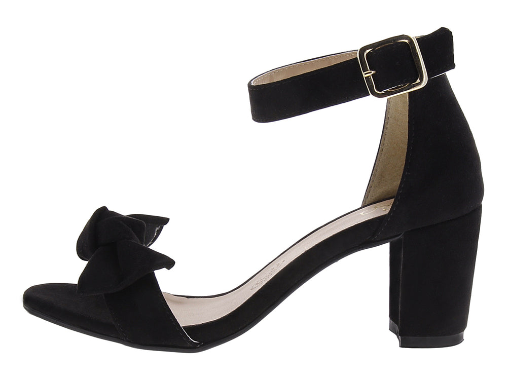 Sandalias negras de tacón grueso con moño frontal y correa al tobillo con hebilla dorada.