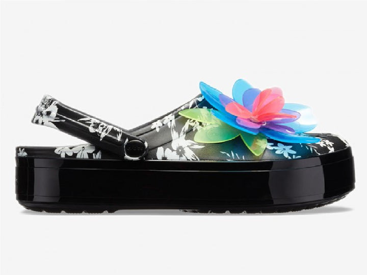 Zuecos Crocs negros con plataforma, estampado floral y una gran flor decorativa en colores neón.