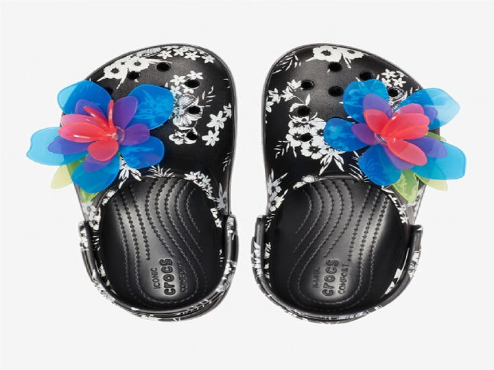 Zuecos Crocs negros con plataforma, estampado floral y una gran flor decorativa en colores neón.