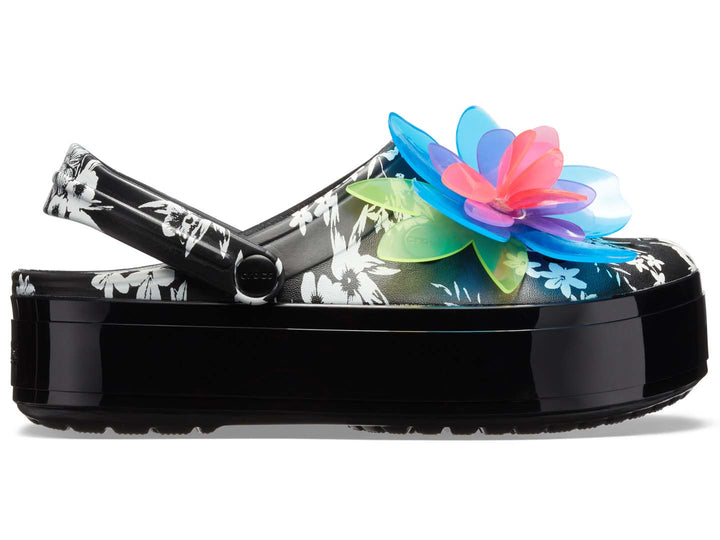 Zuecos Crocs negros con plataforma, estampado floral y una gran flor decorativa en colores neón.