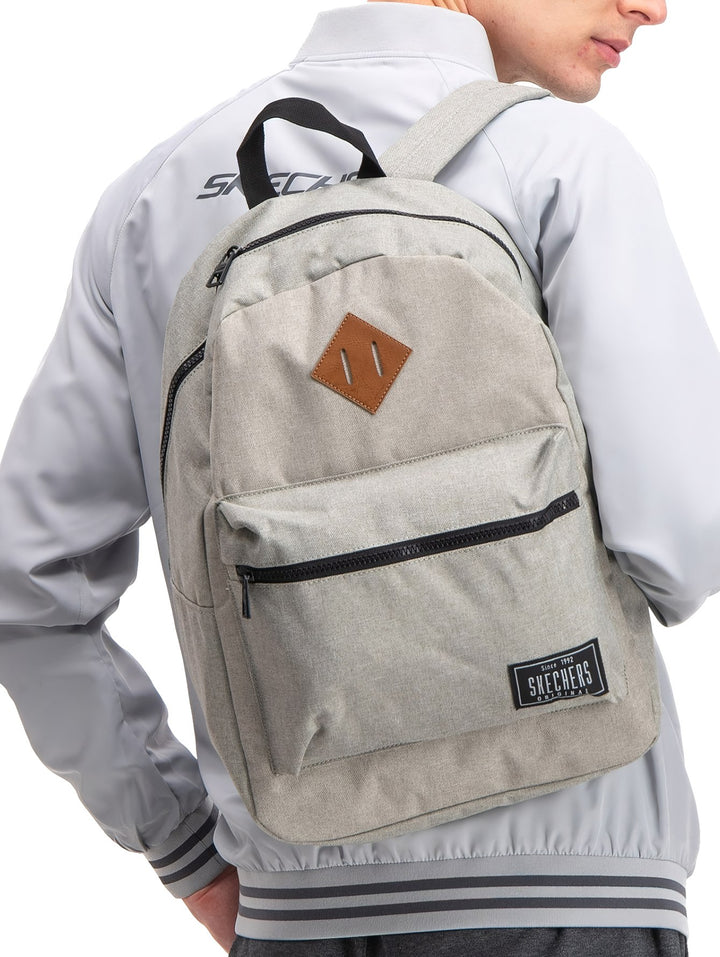 Mochila escolar Skechers de color gris con bolsillo frontal con cierre y detalle en cuero café.