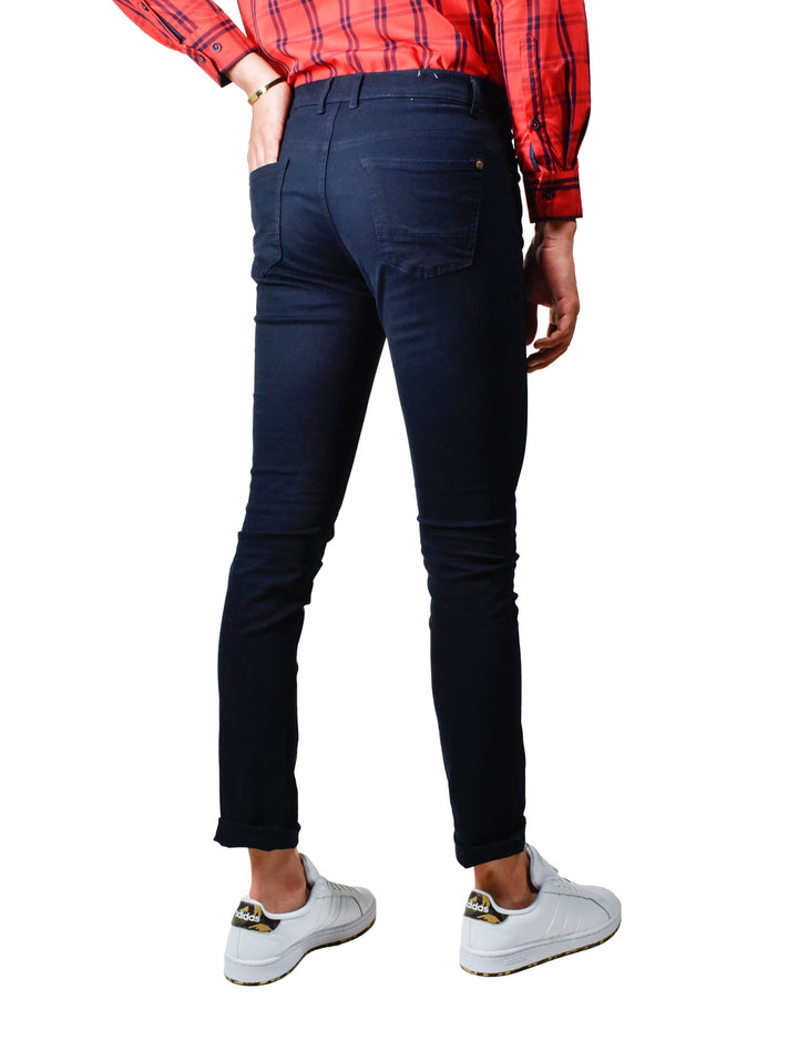 Hombre vistiendo pantalón ajustado color marino con tenis blancos y camisa a cuadros roja.