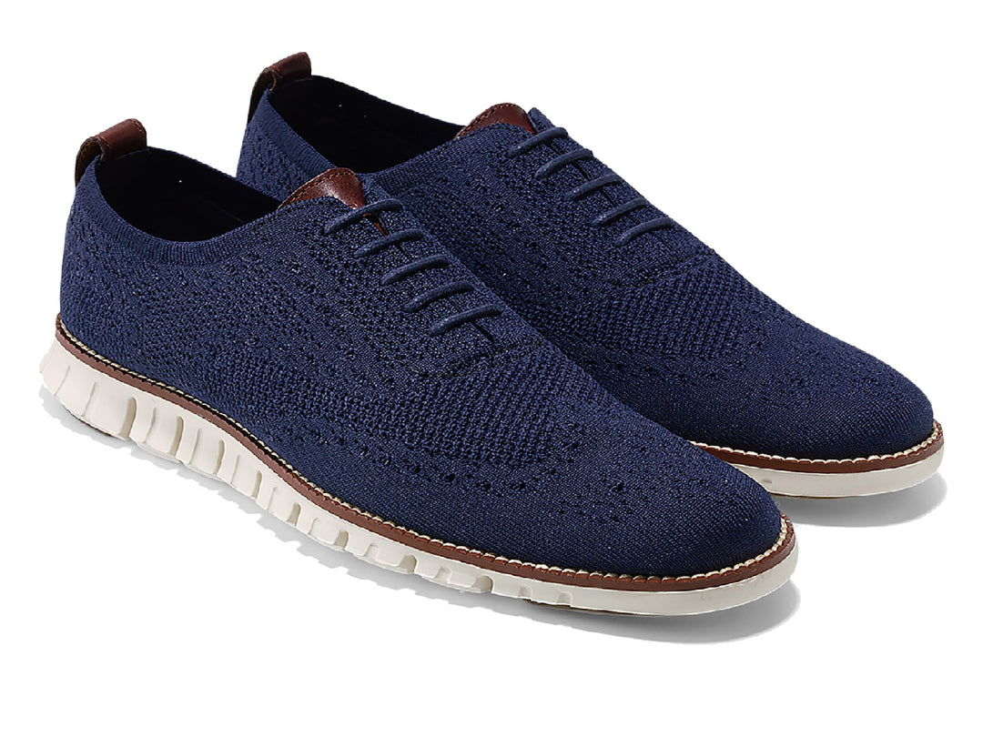 Par de zapatos casuales Cole Haan en color azul marino con suela blanca y detalles en café.