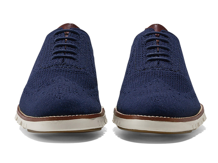 Par de zapatos casuales Cole Haan en color azul marino con suela blanca y detalles en café.