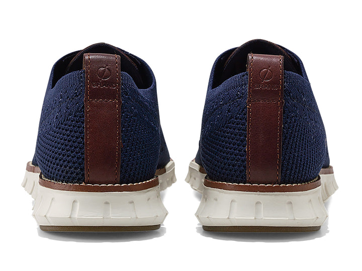 Par de zapatos casuales Cole Haan en color azul marino con suela blanca y detalles en café.