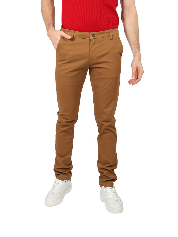 Hombre vistiendo pantalón de gabardina color ocre, playera roja y tenis blancos.
