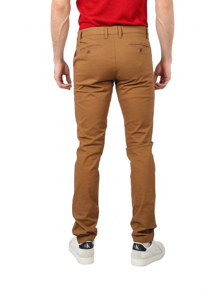 Hombre vistiendo pantalón de gabardina color ocre, playera roja y tenis blancos.