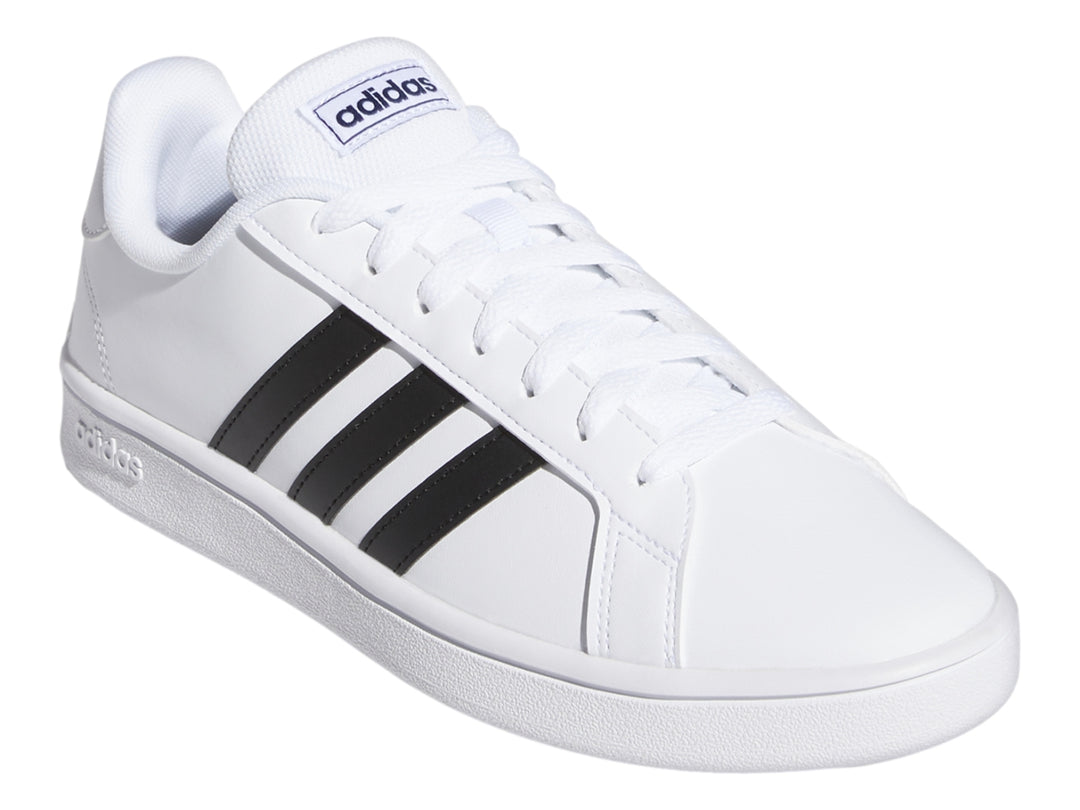 Tenis Adidas Grand Court Base en color blanco con tres franjas negras laterales y suela blanca.