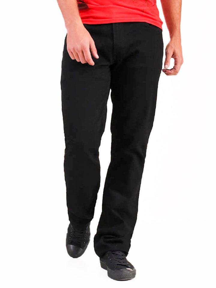 Hombre vistiendo pantalones jeans negros OGGI Vaxter, playera roja y tenis negros sobre fondo blanco.