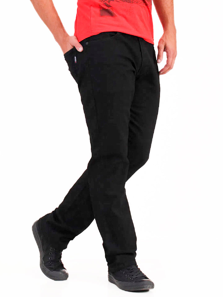 Hombre vistiendo pantalones jeans negros OGGI Vaxter, playera roja y tenis negros sobre fondo blanco.