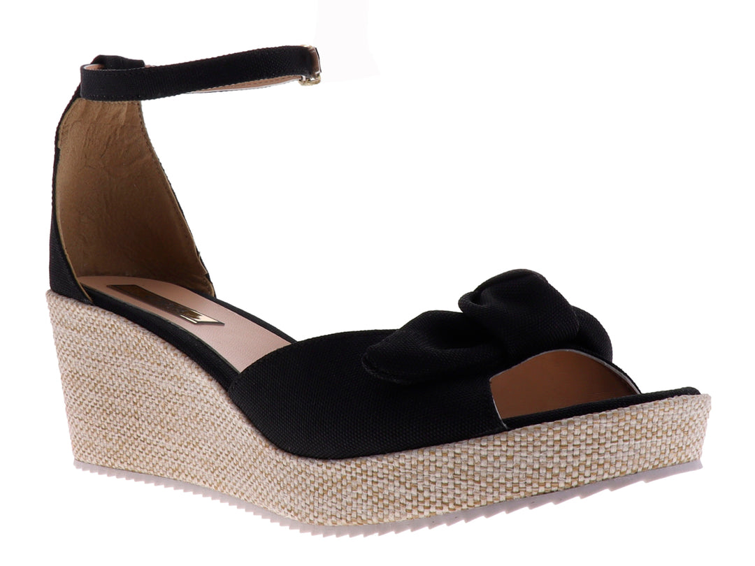 Sandalia de plataforma color negro con moño decorativo y suela de textura tejida en tono beige.