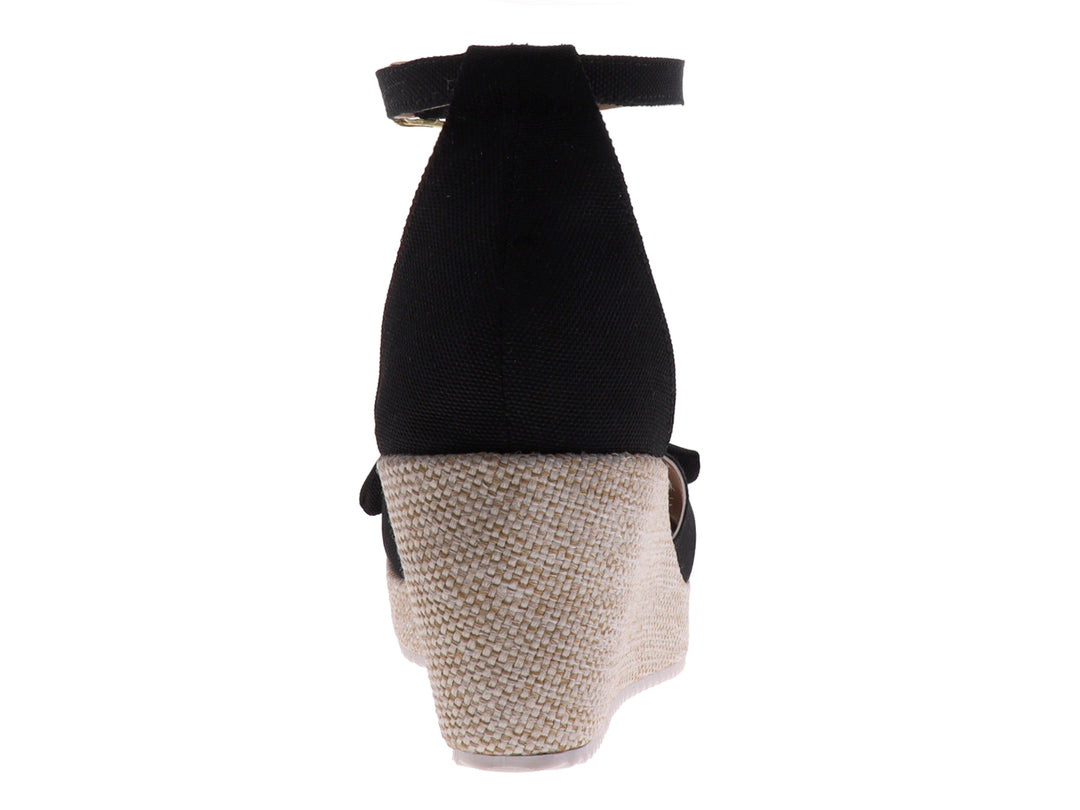 Sandalia de plataforma color negro con moño decorativo y suela de textura tejida en tono beige.