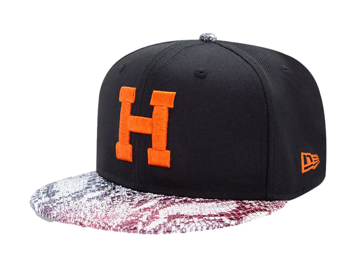 Gorra negra New Era con visera de estampado de piel de serpiente y letra H naranja en el frente.