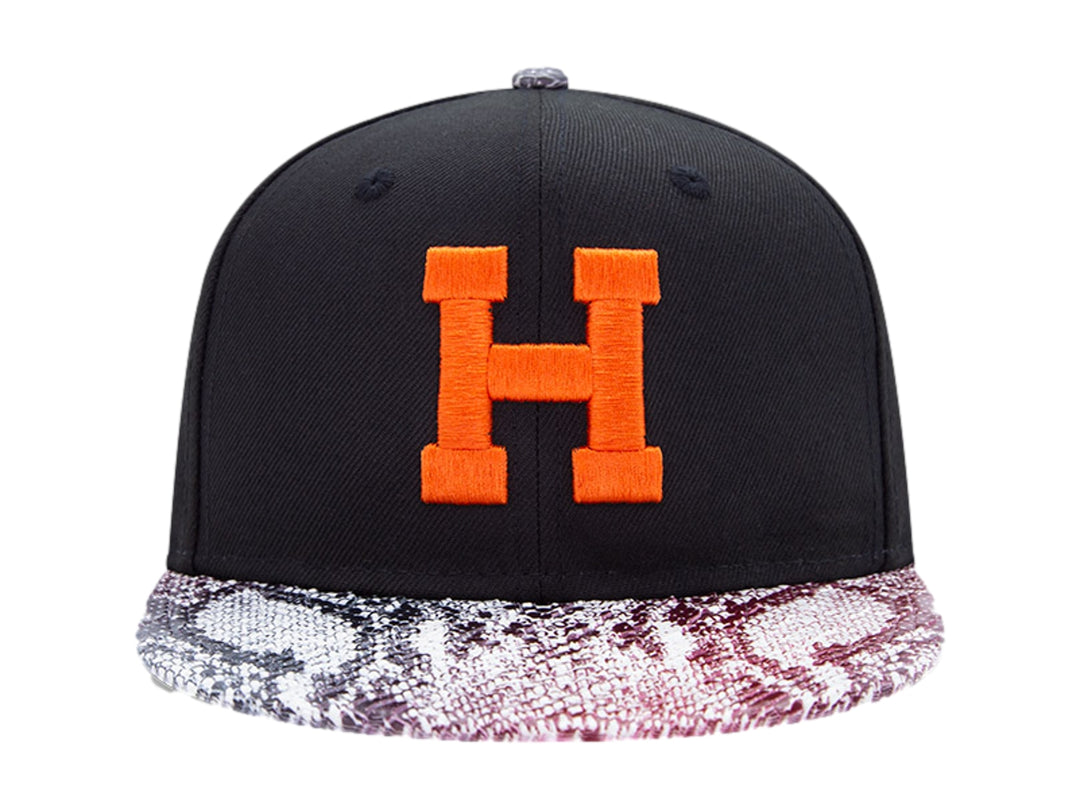 Gorra negra New Era con visera de estampado de piel de serpiente y letra H naranja en el frente.