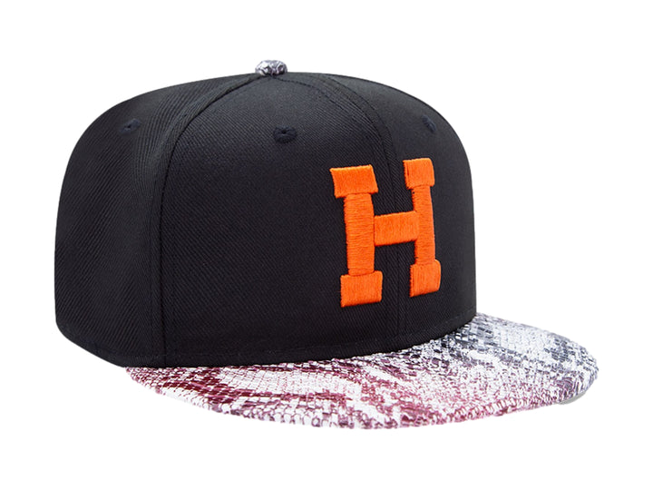 Gorra negra New Era con visera de estampado de piel de serpiente y letra H naranja en el frente.