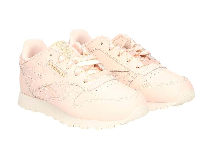 Tenis Reebok Classic Leather color rosa pálido con detalles dorados y suela blanca.
