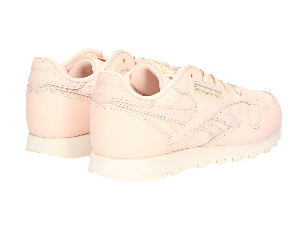 Tenis Reebok Classic Leather color rosa pálido con detalles dorados y suela blanca.