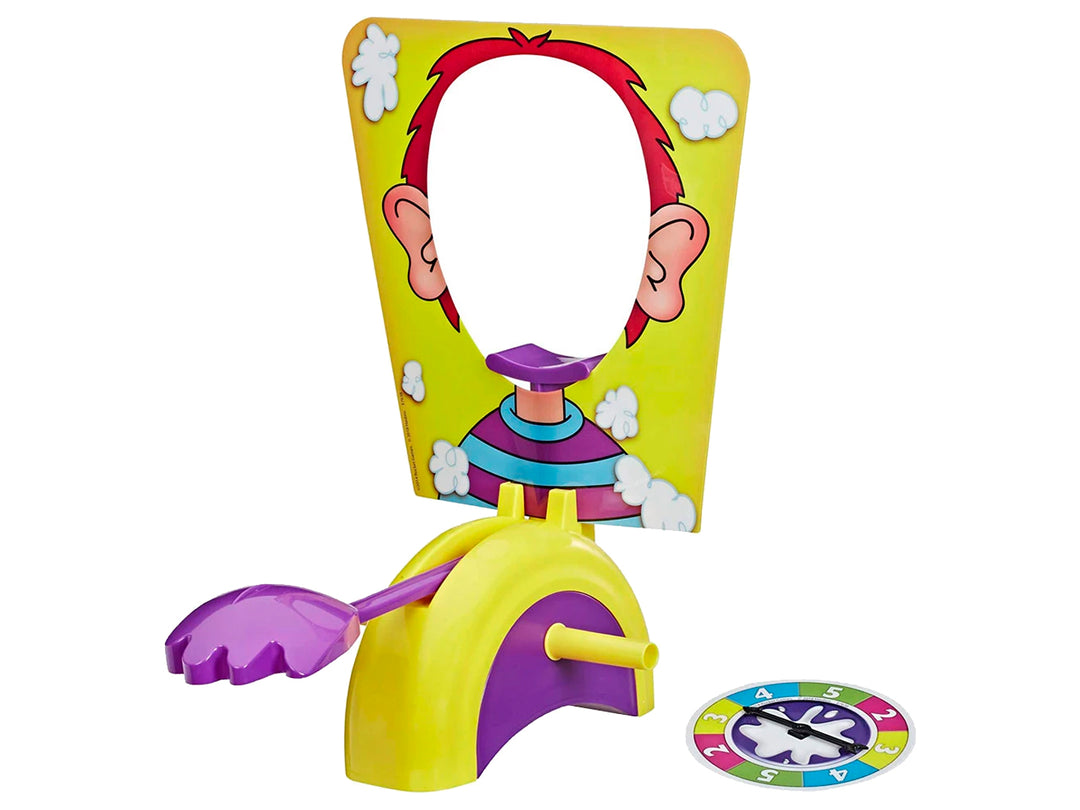 Caja del juego de mesa Pastelazo de Hasbro con fondo amarillo e ilustraciones de niños jugando.