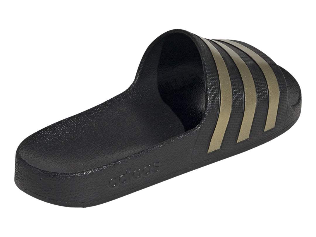 Sandalia Adidas color negro con tres franjas doradas en la correa superior.