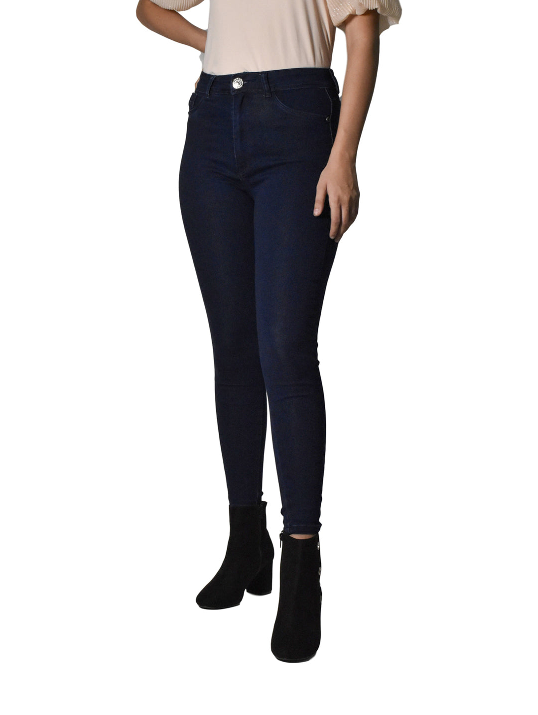 Mujer vistiendo pantalones jeans ajustados de color azul oscuro y botines negros sobre fondo blanco.