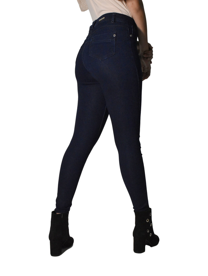 Mujer vistiendo pantalones jeans ajustados de color azul oscuro y botines negros sobre fondo blanco.