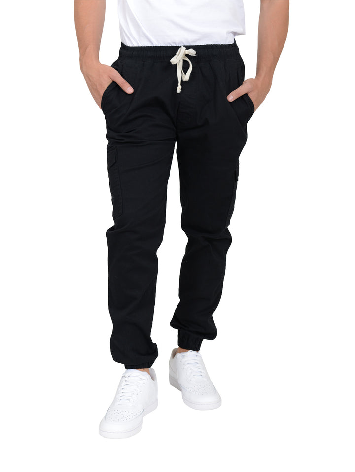 Hombre vistiendo joggers negros con cordones blancos y calzado blanco sobre fondo blanco.