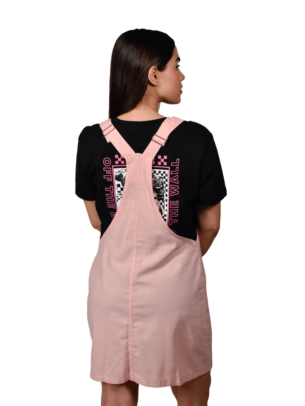 Mujer vistiendo un overol falda color rosa con botones frontales y tirantes sobre una camiseta negra.