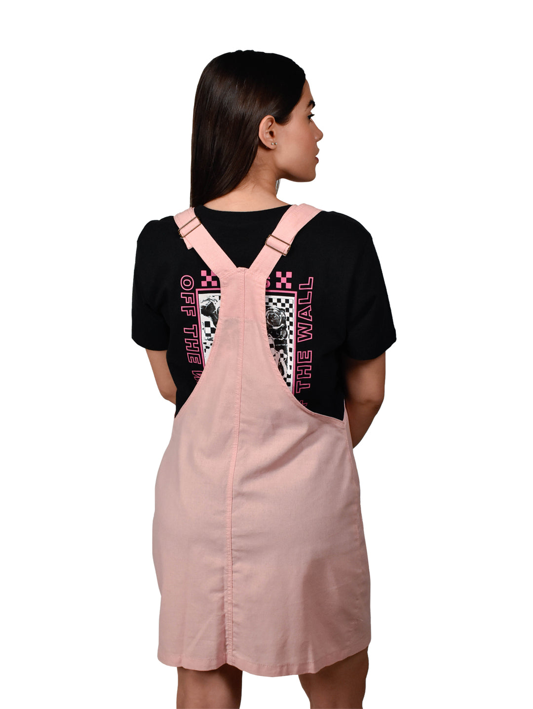 Mujer vistiendo un overol falda color rosa con botones frontales y tirantes sobre una camiseta negra.