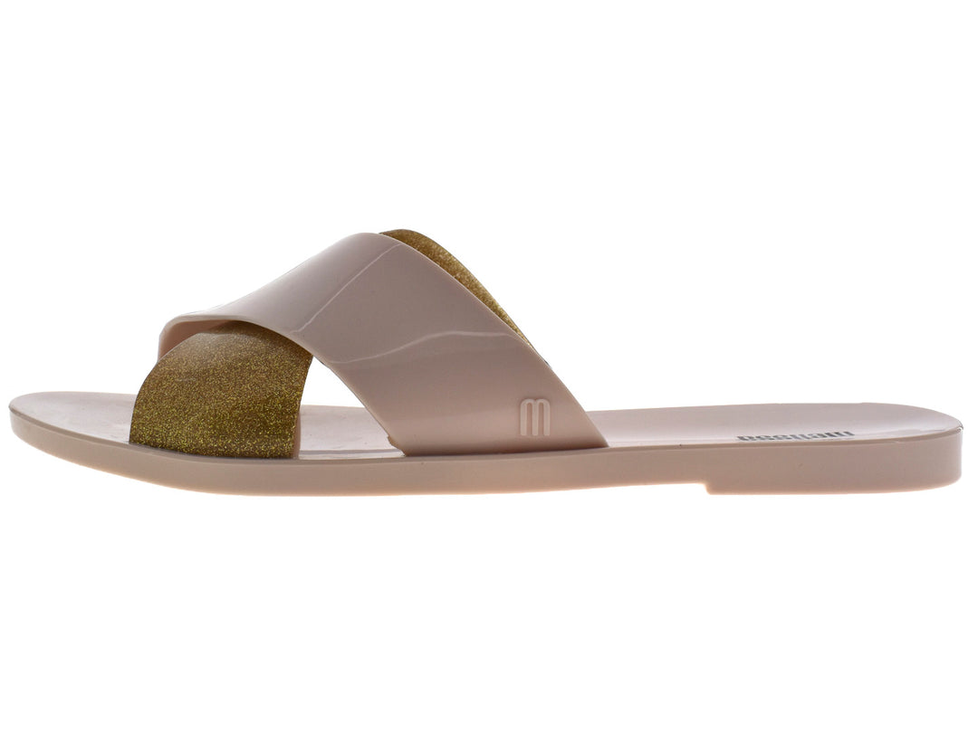 Sandalias slide Melissa color beige con detalle en dorado brillante.